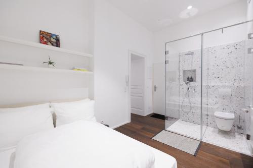 a bedroom with a white bed and a glass shower at Design Apartment Spittelberg - 7th district - contactless checkin in Vienna