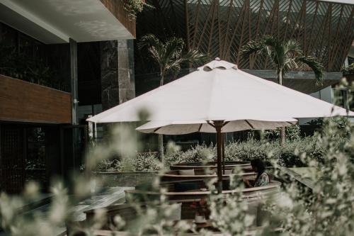 a person sitting under an umbrella in a restaurant at Bellerive Hoi An Resort and Spa in Hoi An