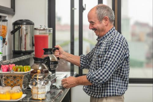 a man standing in a kitchen making a drink in a blender at Media Central Hotel & Spa in Hanoi