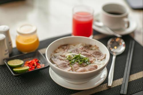 a bowl of soup on a table with a plate of food at Media Central Hotel & Spa in Hanoi