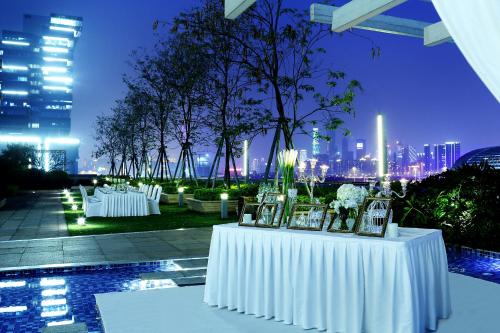 una mesa con manteles blancos y velas en la azotea en Langham Place Guangzhou, en Guangzhou