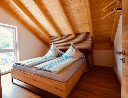 a bed in a room with a wooden ceiling at Ferienwohnungen Ebner in Bischofsmais