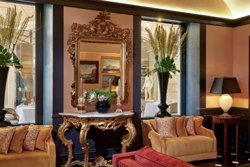 ローマにあるホテル ディンギルテッラ ローマ スター コレツィオーネの鏡、テーブル、椅子が備わる客室です。