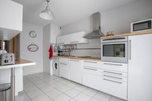 a kitchen with white cabinets and white appliances at Appart Tout Confort in Guillestre