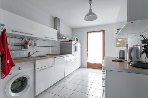 a white kitchen with a washing machine in it at Appart Tout Confort in Guillestre