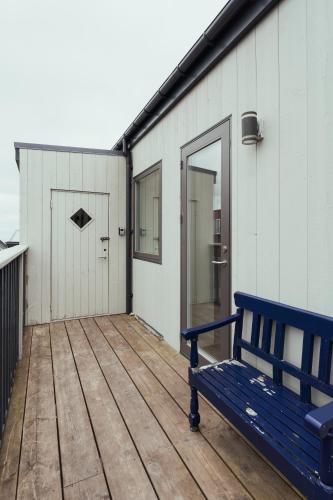 a blue bench sitting on a wooden deck with a building at Delightful 2 Bedroom Apt - Balcony - Parking in Tórshavn