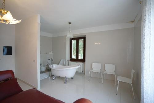 un bagno bianco con vasca e sedie bianche di Villa Helma Lago Maggiore a Caravate