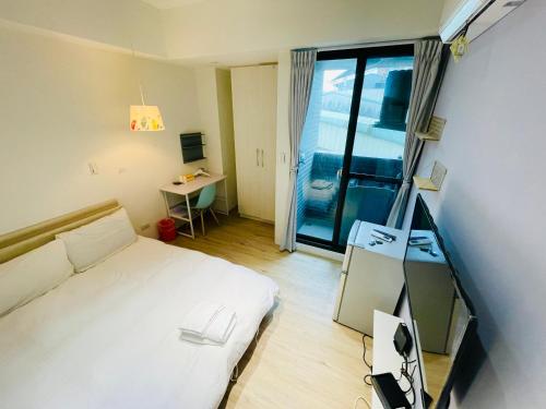 a bedroom with a bed and a desk and a window at 台中 晴文旅 in Taichung