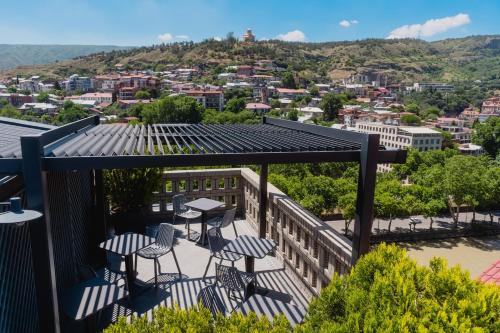 a balcony with tables and chairs and a view of a city at Sandali Metekhi Boutique Hotel in Tbilisi City