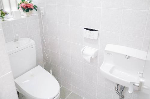 a white bathroom with a toilet and a sink at 青嵐ペンション海まで50M Pension Seiran is only 50m from the coast in Isa