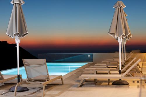 a row of chairs and umbrellas on a swimming pool at Sky View Suites Kefalonia in Vovikes