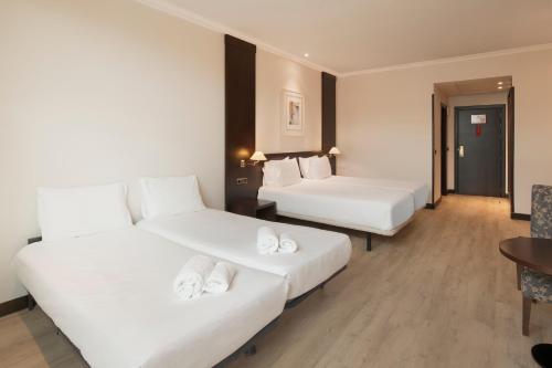 a hotel room with two beds and a table at Exe Oviedo Centro in Oviedo