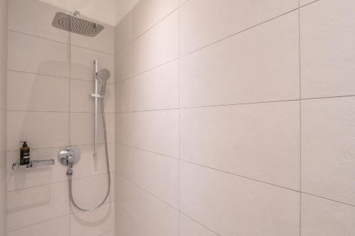 a shower in a white tiled bathroom at Villa by @ Home Hotel Locarno in Locarno