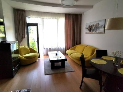 a living room with a yellow couch and a table at Vita Apartment in Druskininkai