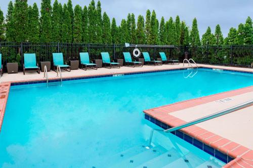 a swimming pool with blue lounge chairs next to a fence at Residence Inn Huntsville in Huntsville