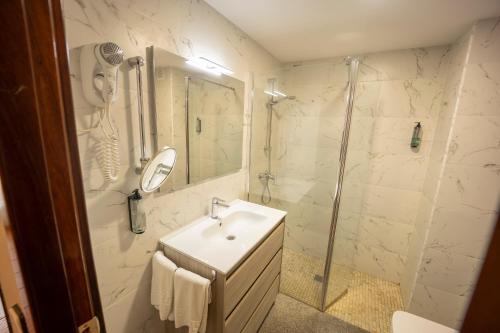 a white bathroom with a sink and a shower at Hotel Florida in San Lorenzo de El Escorial