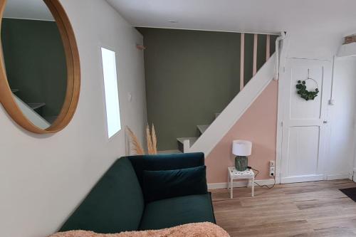- un salon avec un canapé vert et un miroir dans l'établissement Bright little house in Douvres-la-Délivrande, à Douvres-la-Délivrande