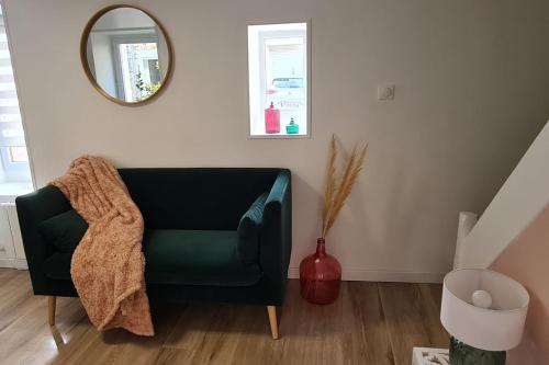 - une chaise verte dans le salon avec un miroir dans l'établissement Bright little house in Douvres-la-Délivrande, à Douvres-la-Délivrande