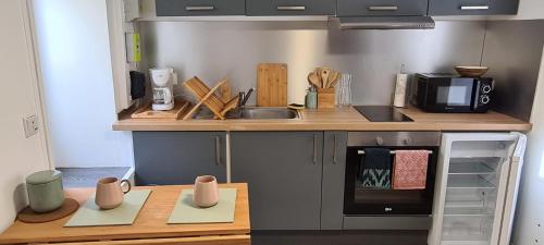 - une cuisine avec un comptoir, un évier et une cuisinière dans l'établissement Bright little house in Douvres-la-Délivrande, à Douvres-la-Délivrande
