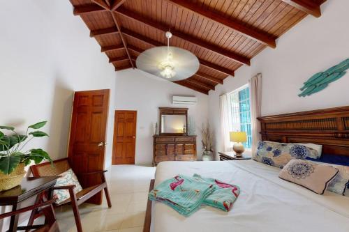 a bedroom with a large white bed with a wooden ceiling at Kismet Garden Cottages - Dover Beach in Christ Church