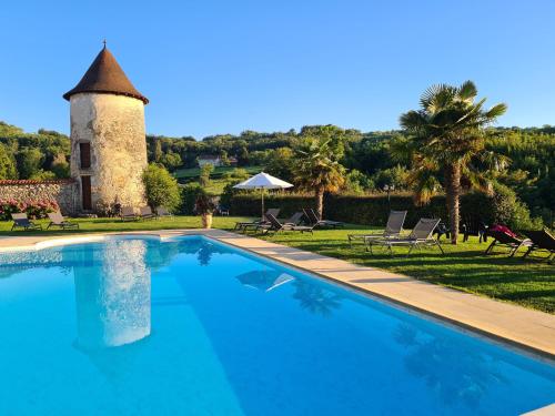 a swimming pool in front of a building with a tower at Les Dépendances de Chapeau Cornu in Vignieu