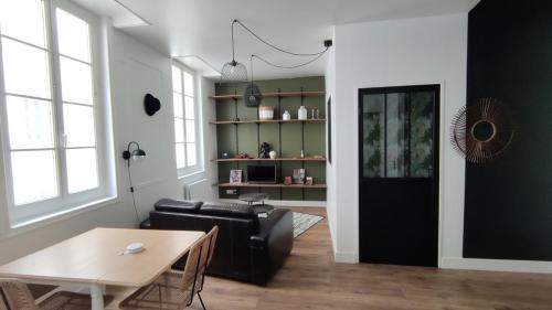 sala de estar con sofá negro y mesa en Le Tréville Grand Studio Cosy 32M2, en Rochefort