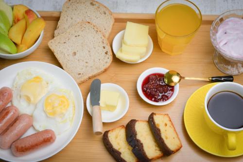 a table with a breakfast of eggs sausage and bread and coffee at Surami Guest House - სახლი სურამში in Surami