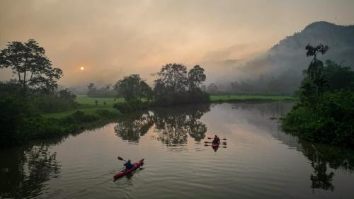two people in kayaks on a river at sunset at Singharaja Garden AGRO ECO Lodge in Pelawatta
