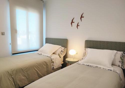 twee bedden in een kamer met twee vogels aan de muur bij Apartamento con solarium en Jardines de Montesolana in Alicante