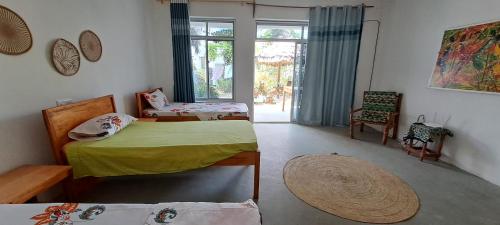 1 dormitorio con 2 camas, silla y ventana en Karibu House, en Paje