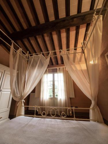 a bedroom with a bed with curtains and a window at ISA-Residence with swimming-pool in Monteverdi Marittimo in Monteverdi Marittimo