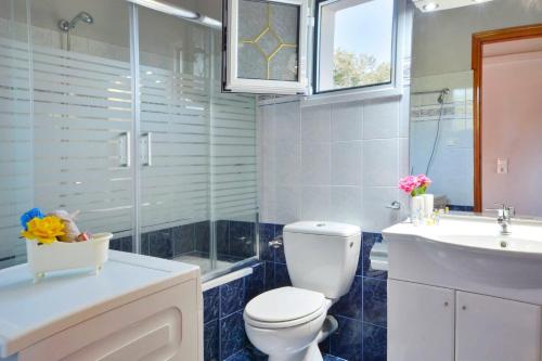a bathroom with a toilet and a sink at Tranquil Corfu Villa - 3 Bedrooms - Villa Chrinos - Gated Pool - Agios Georgios Pagon in Agios Georgios Pagon