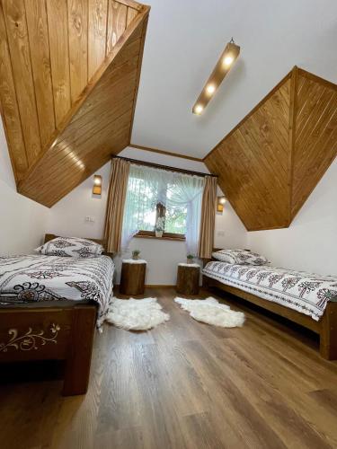 two beds in a room with wooden ceilings at Leszczyniański Domek in Biały Dunajec