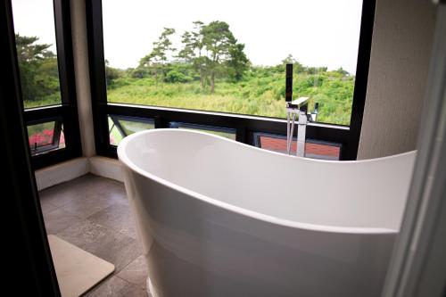 a white bath tub in a bathroom with a window at Hyeopjae Claire de lune in Jeju