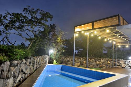 a swimming pool in front of a building with lights at Hyeopjae Claire de lune in Jeju