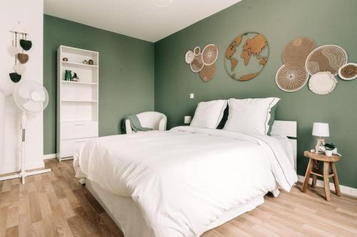 sypialnia z białym łóżkiem i zieloną ścianą w obiekcie Élégance Proche Disneyland w mieście Serris