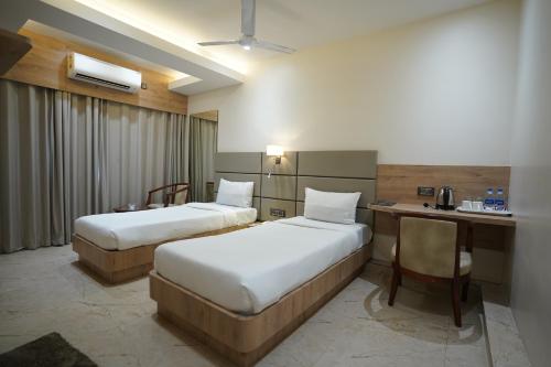 Habitación de hotel con 2 camas y escritorio en HOTEL THE VENUE en Dhanbād