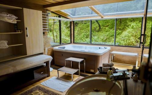 ein Bad mit einer Badewanne und einem großen Fenster in der Unterkunft Dolina Retreat in Masuri