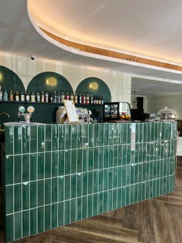 um balcão de azulejos verdes num quarto com um bar em Mleczarnia Hotel Restauracja em Chludowo