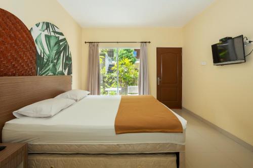 a bedroom with a bed with a television and a window at Cove Kanaya in Seminyak