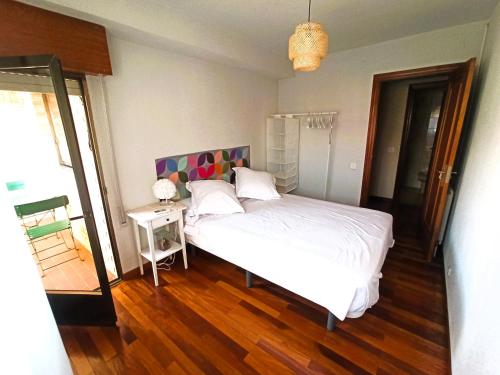 1 dormitorio con cama blanca y suelo de madera en LA BOTICA DEL MONASTERIO, en Sahagún