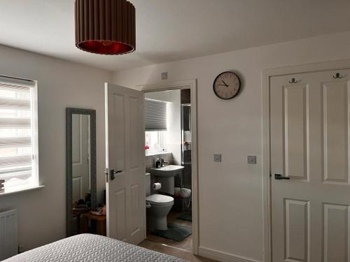 a bedroom with a bed and a clock on the wall at Double Room in a Family Home - 15 Minutes Walk to Famous Bicester Village in Chesterton