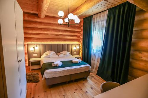 ein Schlafzimmer mit einem Bett in einem Blockhaus in der Unterkunft PENSIUNEA IZABELLA, Izabella Chalet in Topliţa