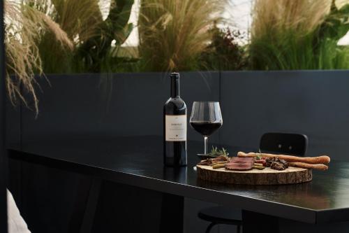 a bottle of wine and a plate of food and a wine glass at The Newel Psychiko in Athens
