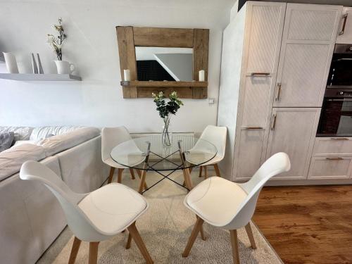 Fantastic 2-Bed House with Parking - Hosted by Hutch Lifestyle في ليمينغتون سبا: غرفة معيشة مع طاولة زجاجية وكراسي بيضاء