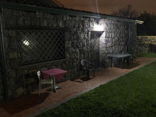 a stone wall with two chairs and a table at night at Il Rustico in Pozzillo