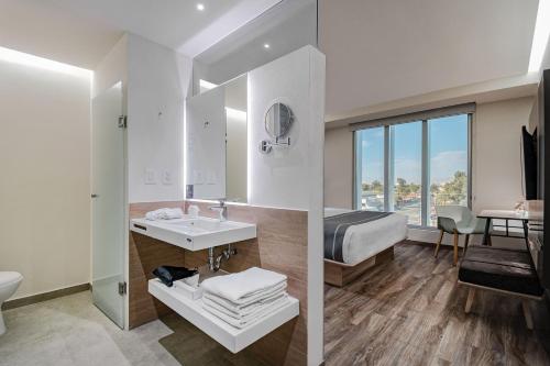 a bathroom with a sink and a bedroom with a bed at City Express Plus by Marriott Mexicali in Mexicali