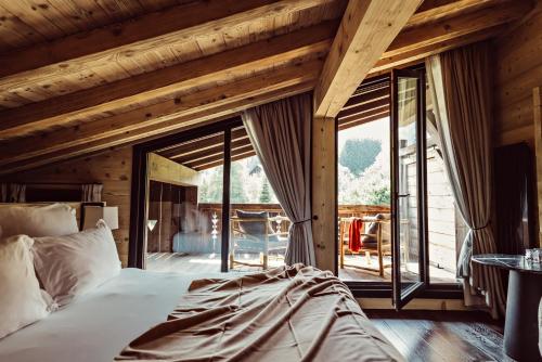 a bedroom with a bed and a large window at L'Alpaga, a Beaumier hotel in Megève