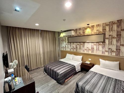 a hotel room with two beds and a tv at Home Full Hotel in Jincheng