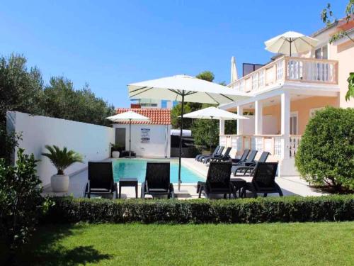 dom z basenem, krzesłami i parasolami w obiekcie Apartments in Biograd na Moru - Biograd Riviera 42685 w Biogradzie na Moru